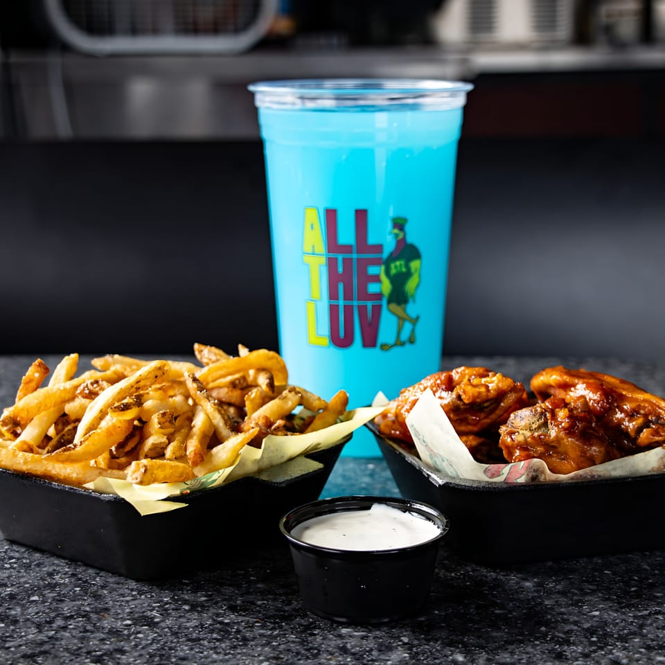 ATL Wings meal with golden fries, saucy wings, a side of ranch, and a blue branded drink.